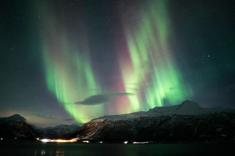 snow covered mountains near body of water during night time