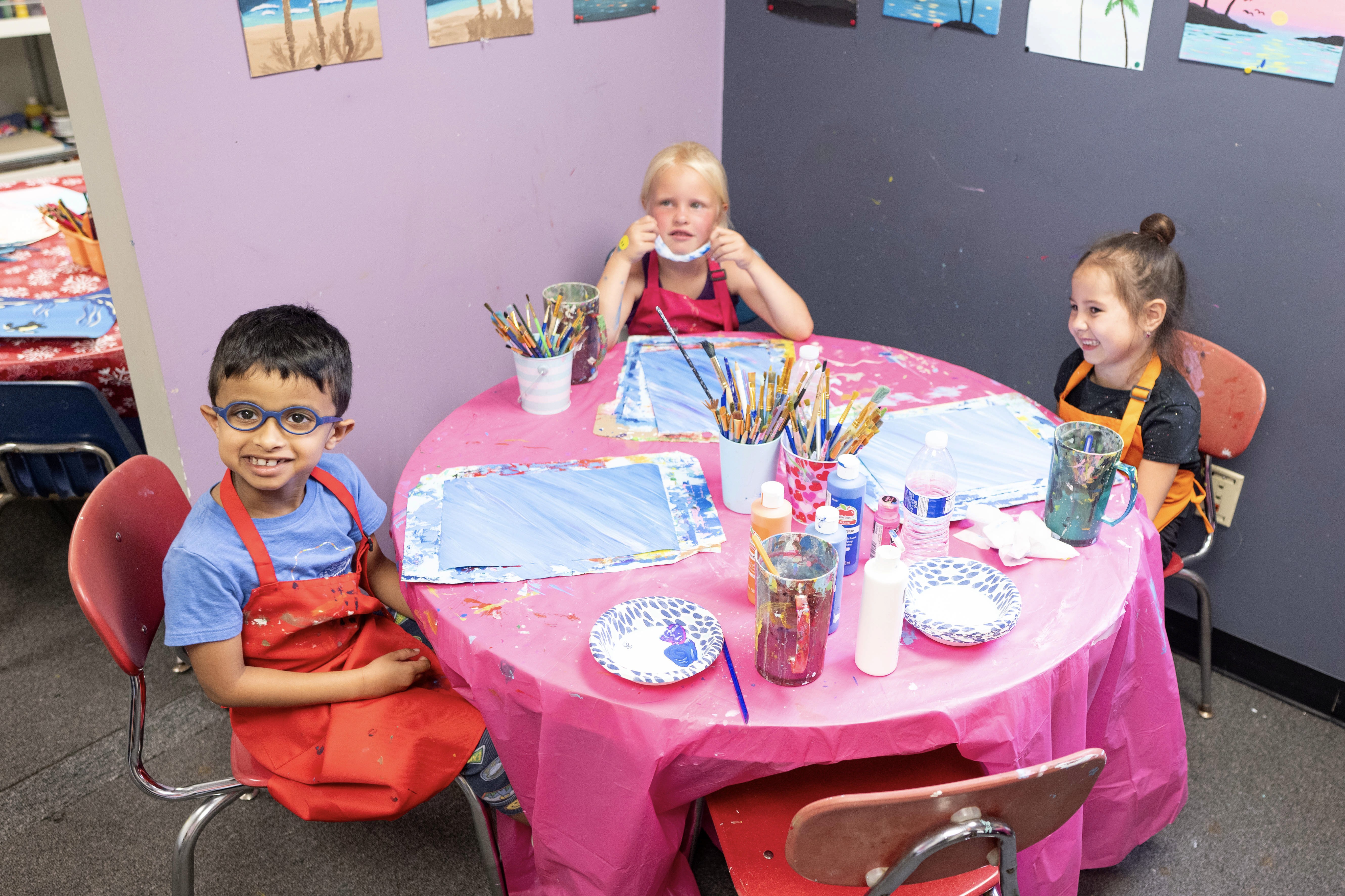Two girls and a boy painting at a table during an art class in the SportPlus art studio