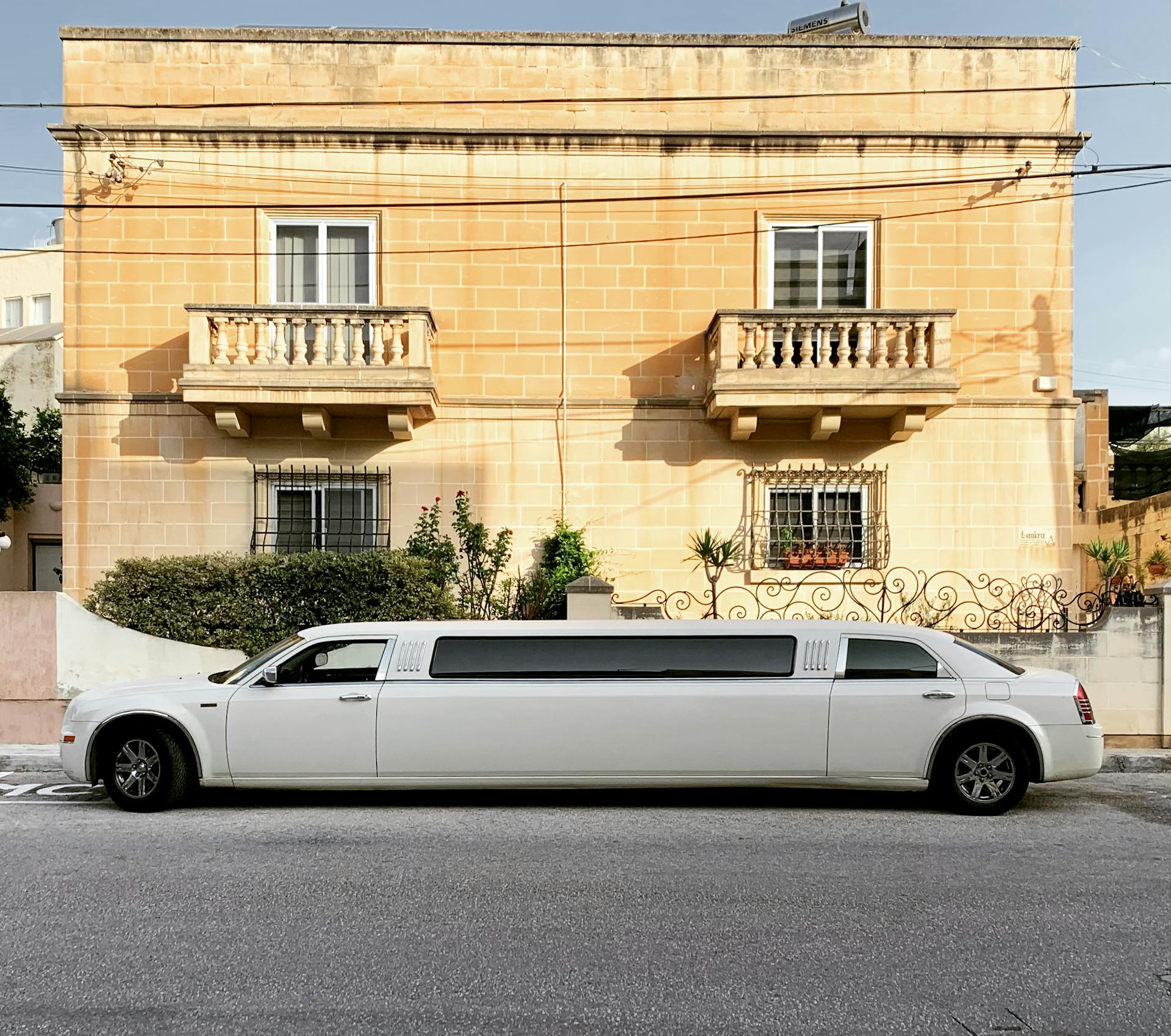 White limousine parked in front of a historic building, symbolizing luxury transportation for wine tours in Long Island.