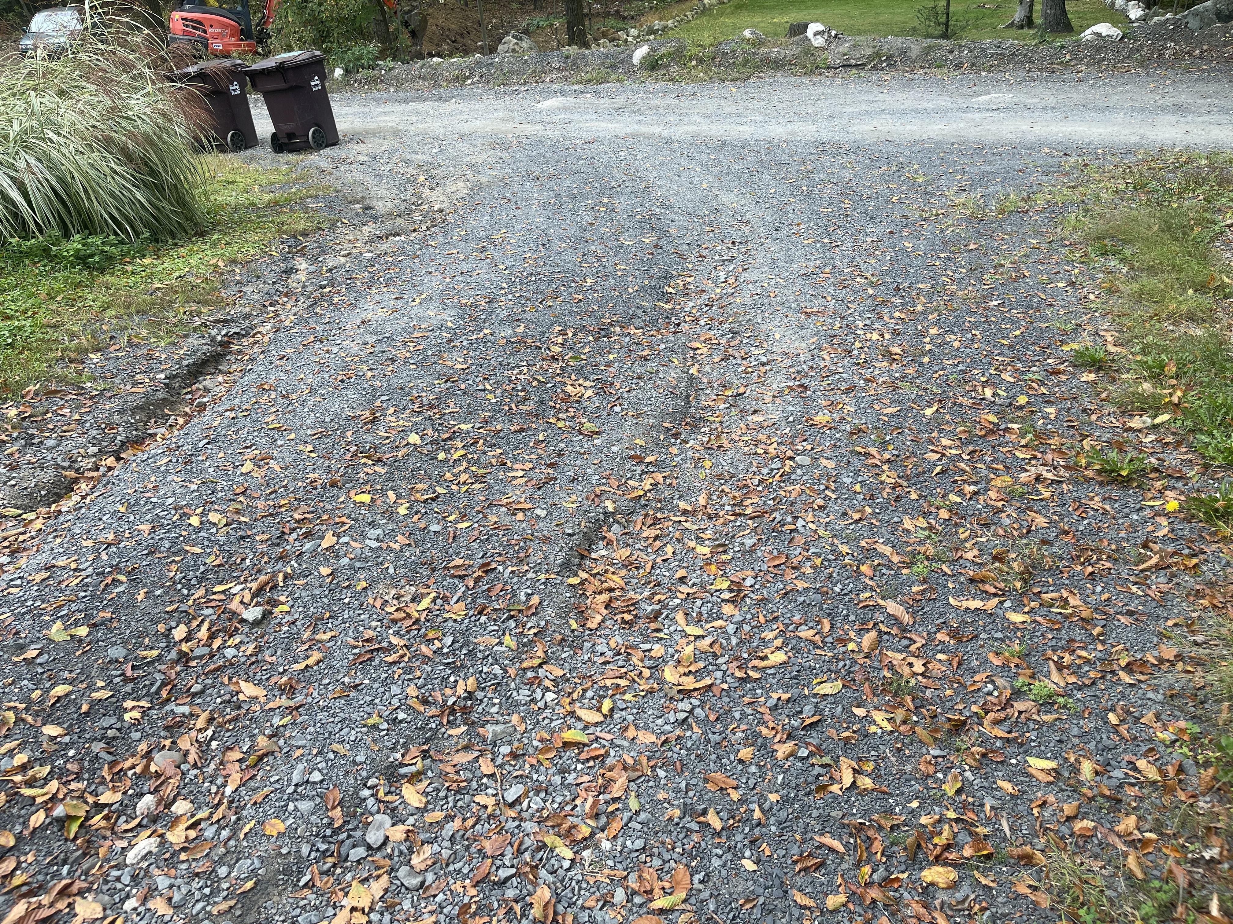 Gravel driveway showing uneven surface wear caused by base and drainage issues