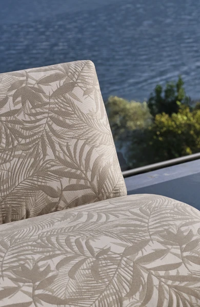 Modern outdoor (مجموعة أثاث متكاملة) furniture scene with curved wooden armchairs in solid Iroko and upholstered cushions, arranged poolside next to tropical greenery – contemporary luxury collection for stylish open-air living spaces