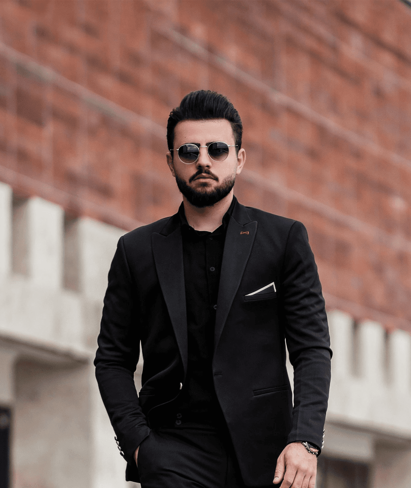 man in black suit jacket and black pants standing on gray concrete floor during daytime