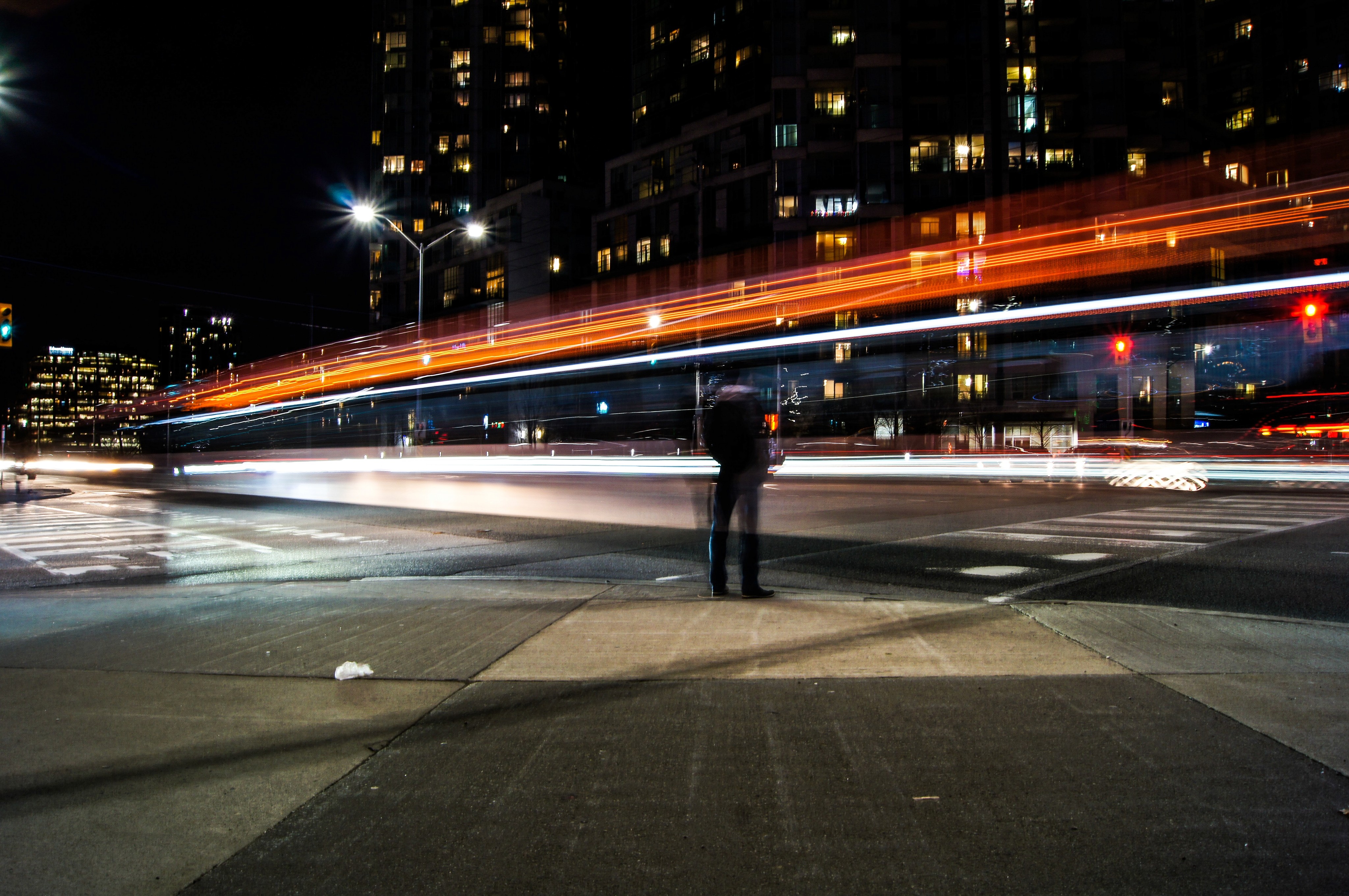 Orange and white light trails from a car in the middle of a city