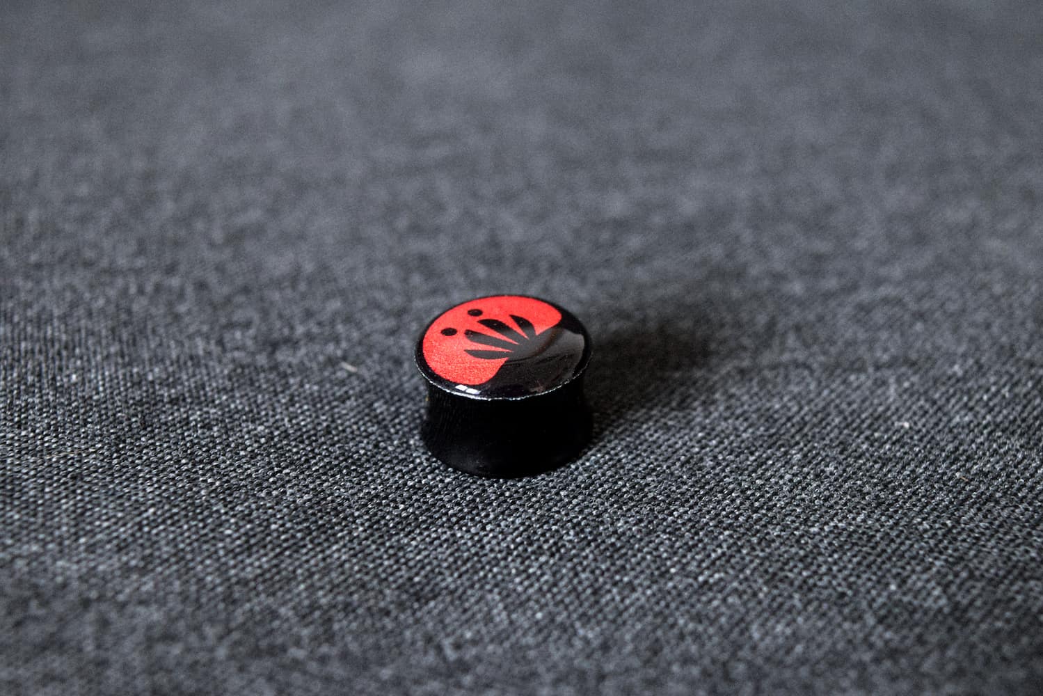 logo mark on ear plug, strecher on grey textured surface.