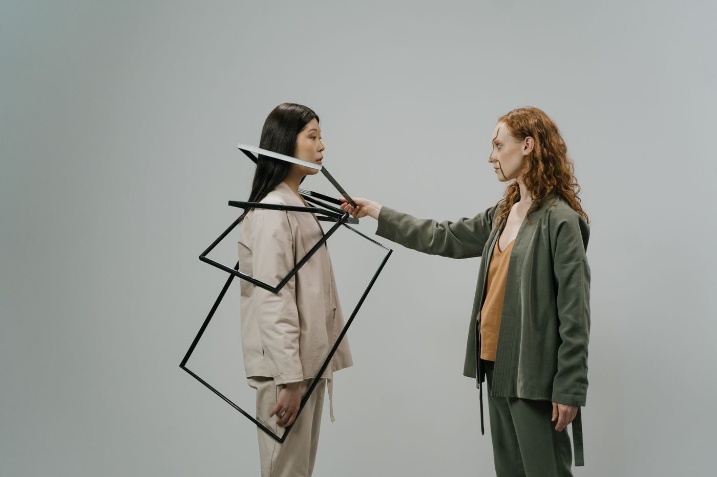 Three models in earth-tone suits with painted faces