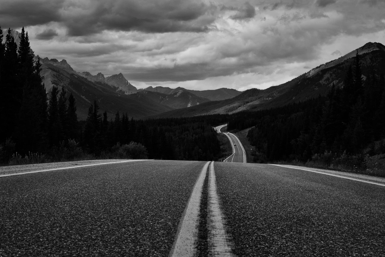 Carretera que se adentra entre montañas, representando la planificación de medios y la dirección estratégica de Mondaymeeting.