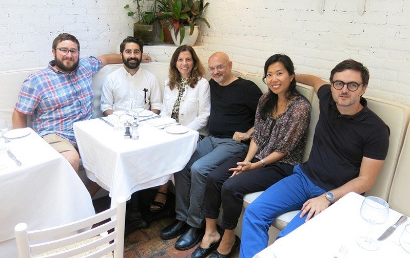 A photo of a group of people sitting around of a restaurant table.