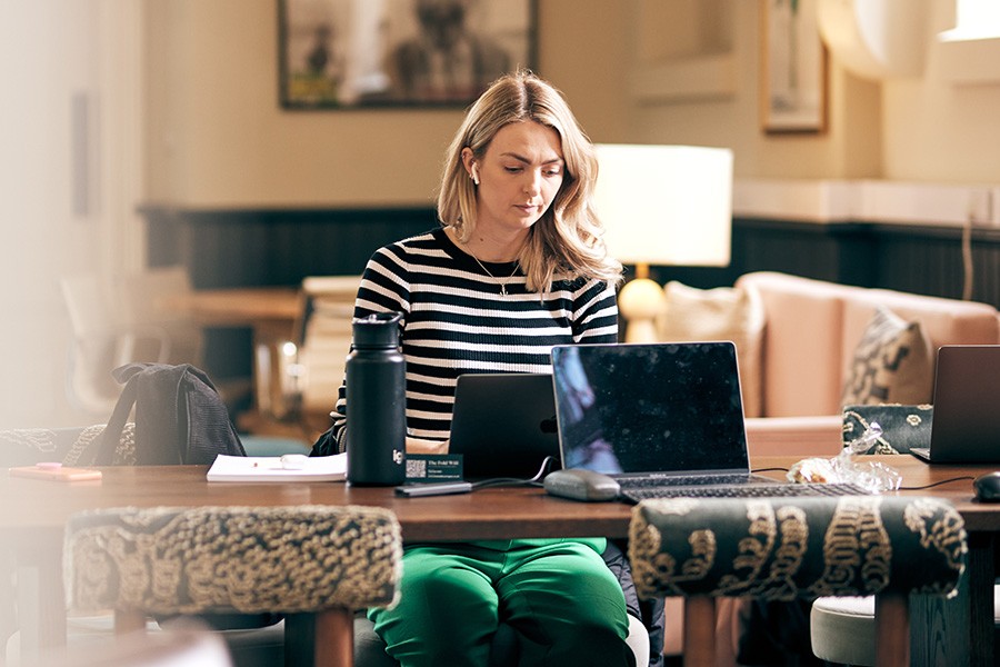 A woman sat at a table using her laptop