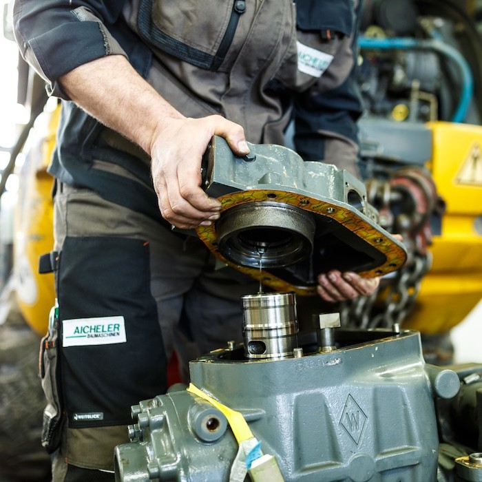Aicheler Mitarbeiter bei mechanischer Reparatur an einem Baumaschinenteil