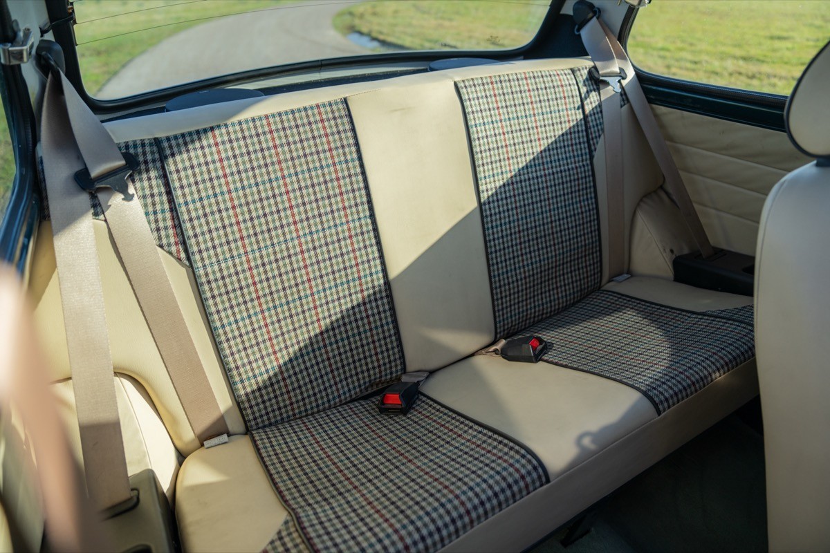 Interior view of a car's backseat, featuring light-colored upholstery and a spacious, clean layout.