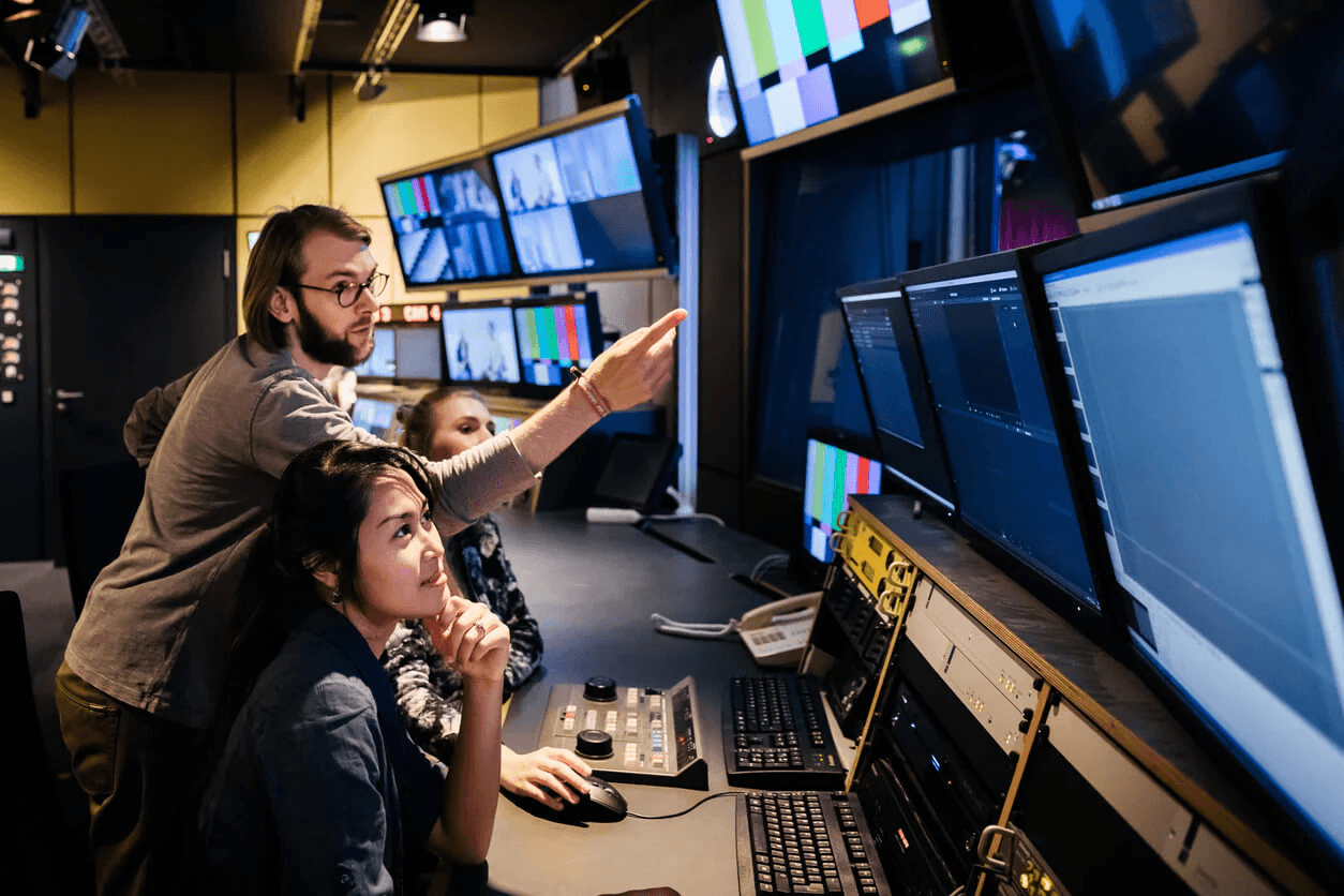 People in a control room with multiple monitors.
