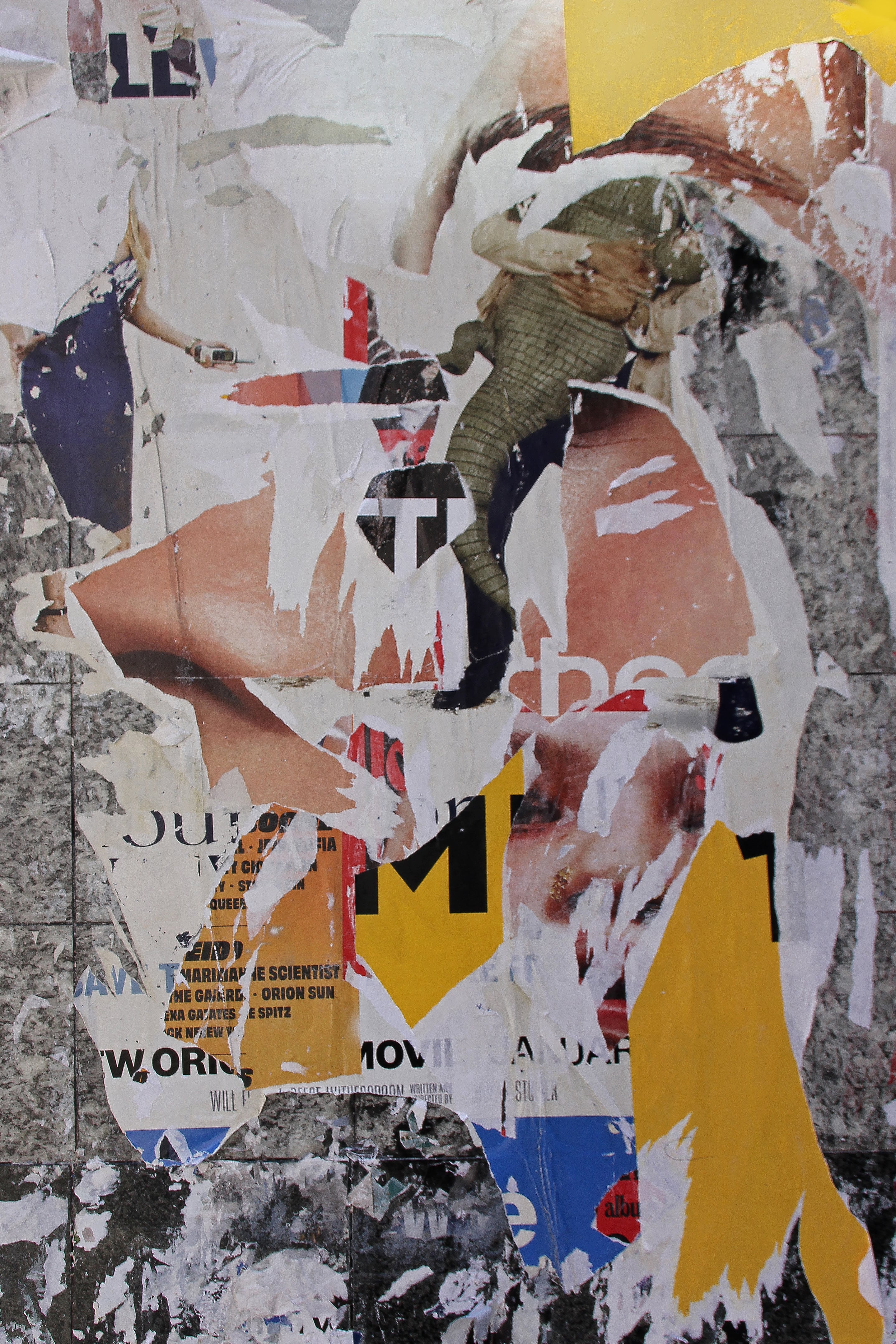 Close-up photograph of layered torn posters featuring fragments of faces, text, and bold yellow shapes. The composition blends skin tones, paper textures, and remnants of color into a dynamic abstract collage that suggests both erosion and renewal.