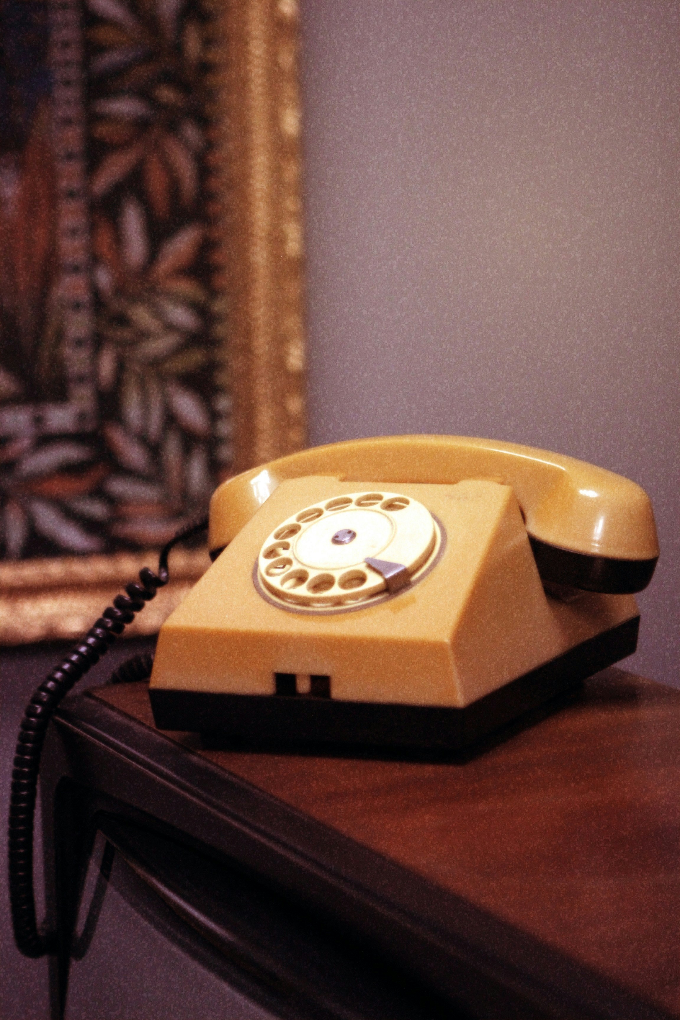 a yellow telephone sitting on top of a wooden table