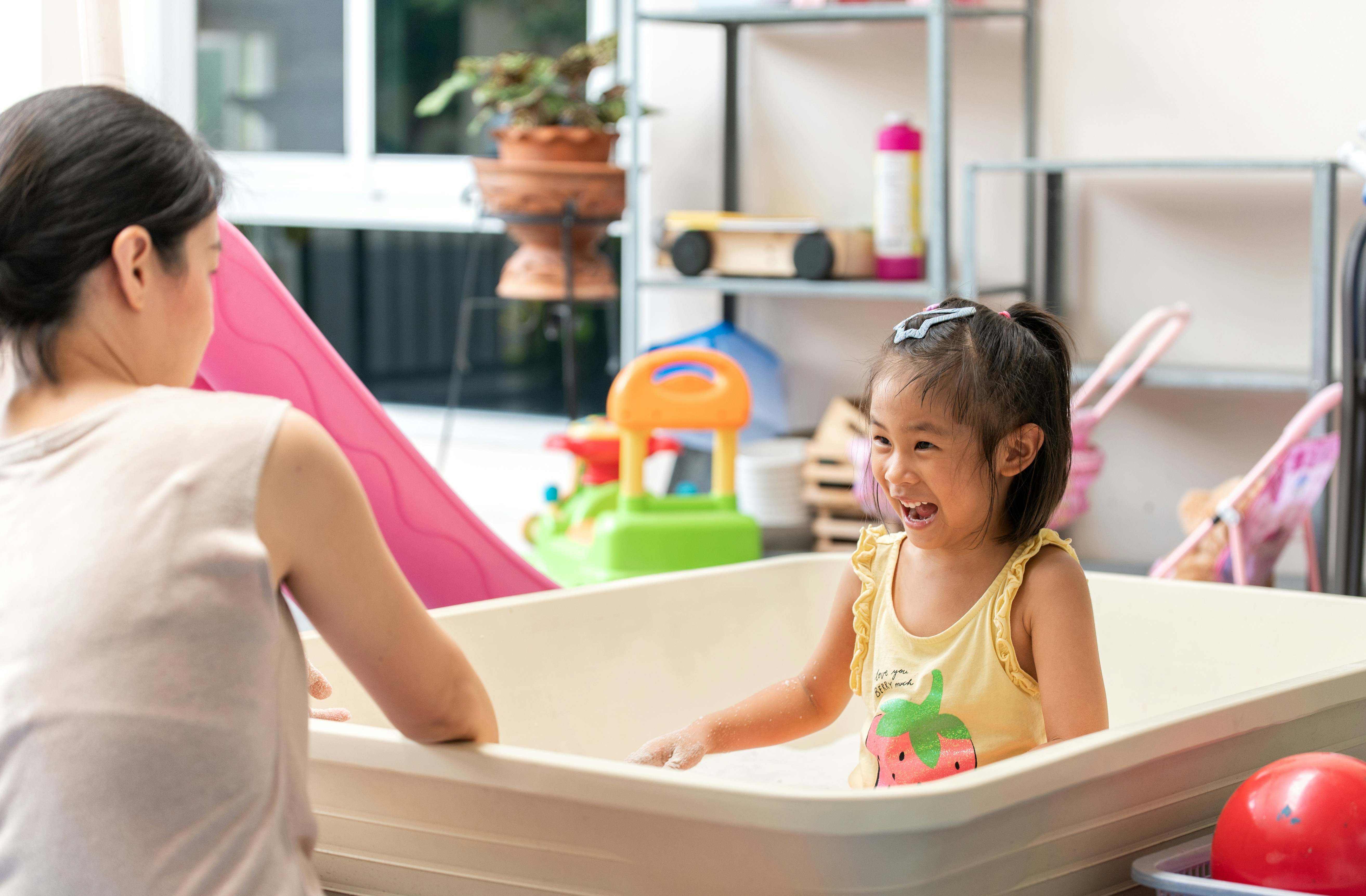 girl in pink tank top sitting on white bathtub