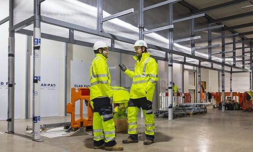 Rooftop garden with trees and plants, overlooking a cityscape at sunset with a tall building in the background