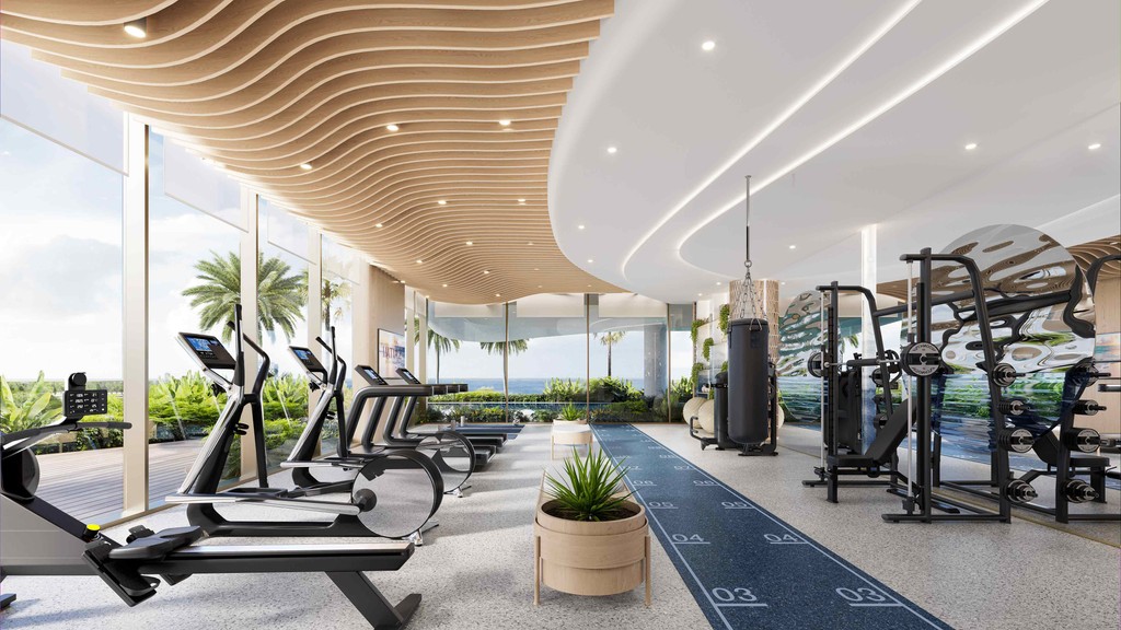 Interior of a gym at Sunset Bay Grand, showcasing exercise equipment with a beautiful ocean view.