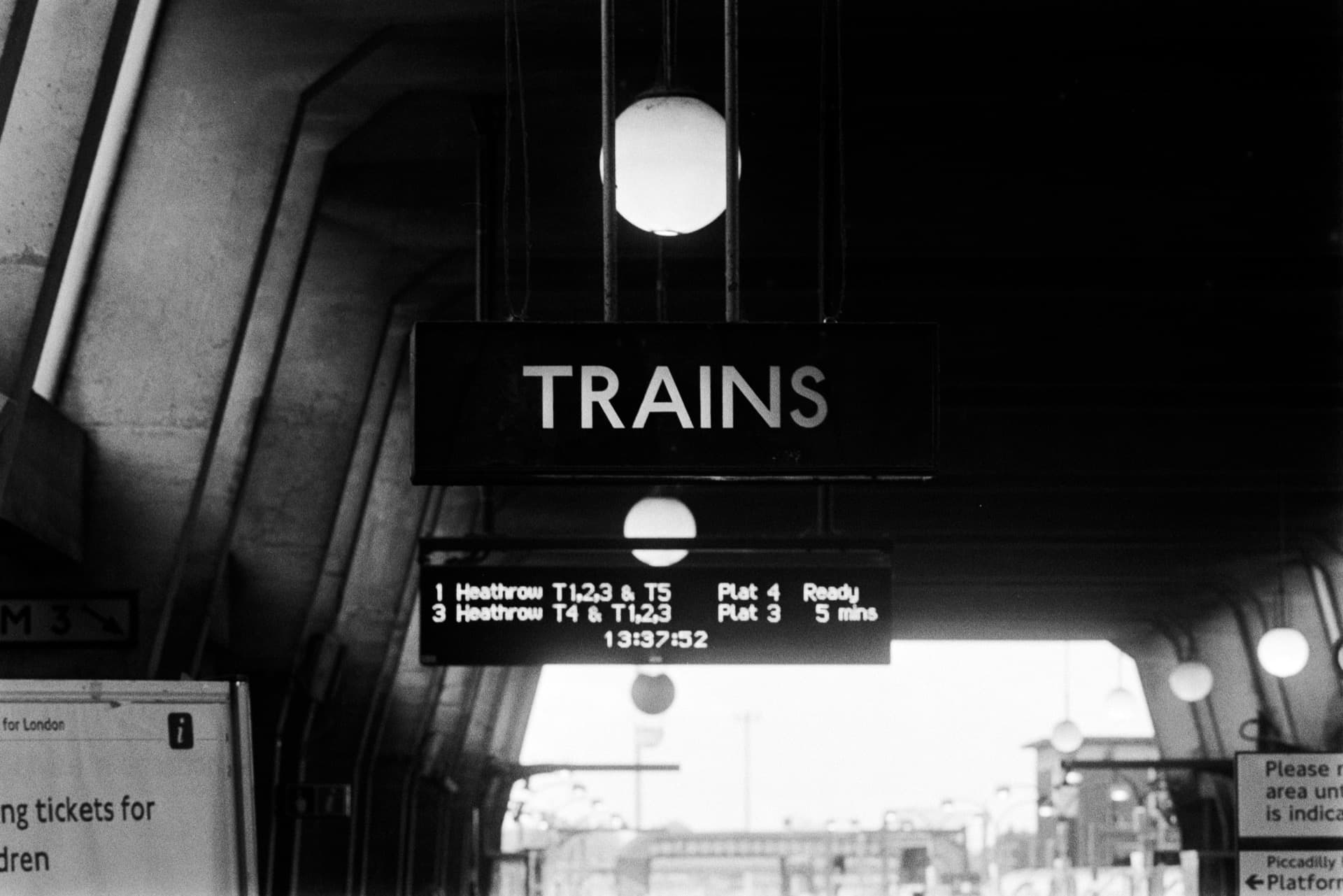 Trains departure sign showing Heathrow services beneath curved station ceiling with platform lighting