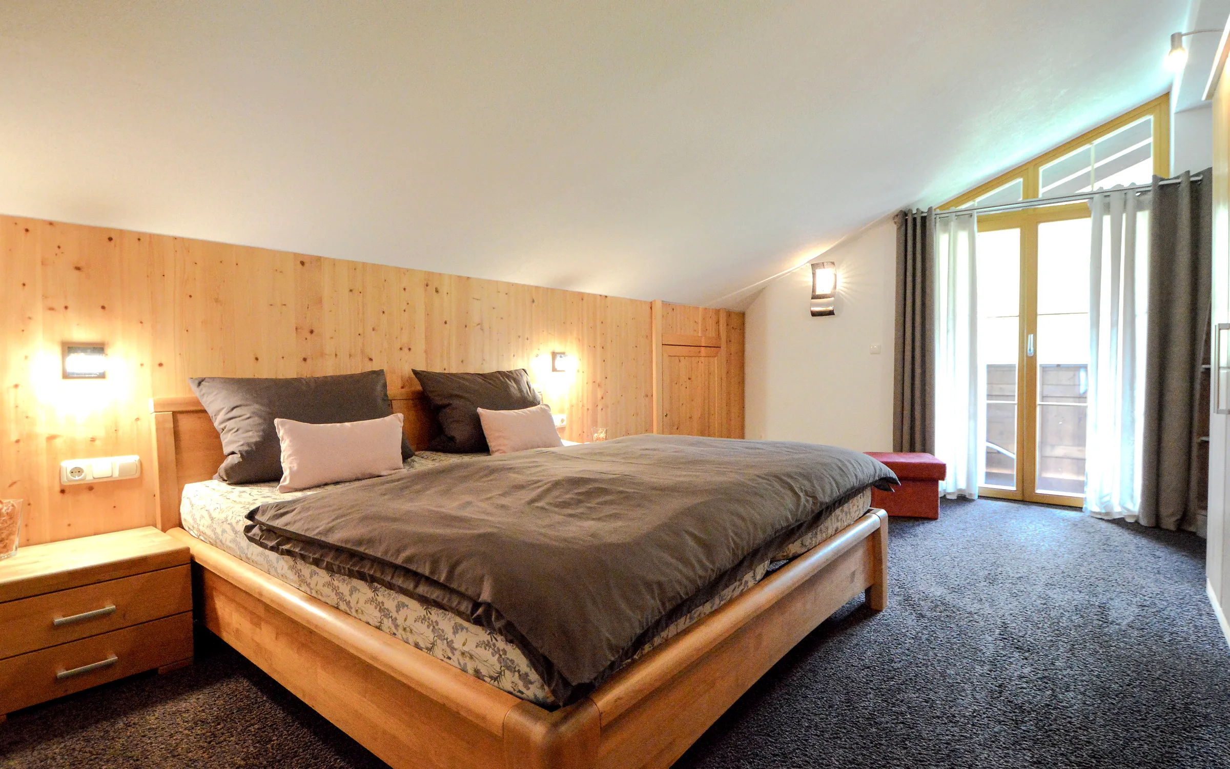 Zweites Schlafzimmer der Ferienwohnung mit Betten, Sitzecke und Holzdecke