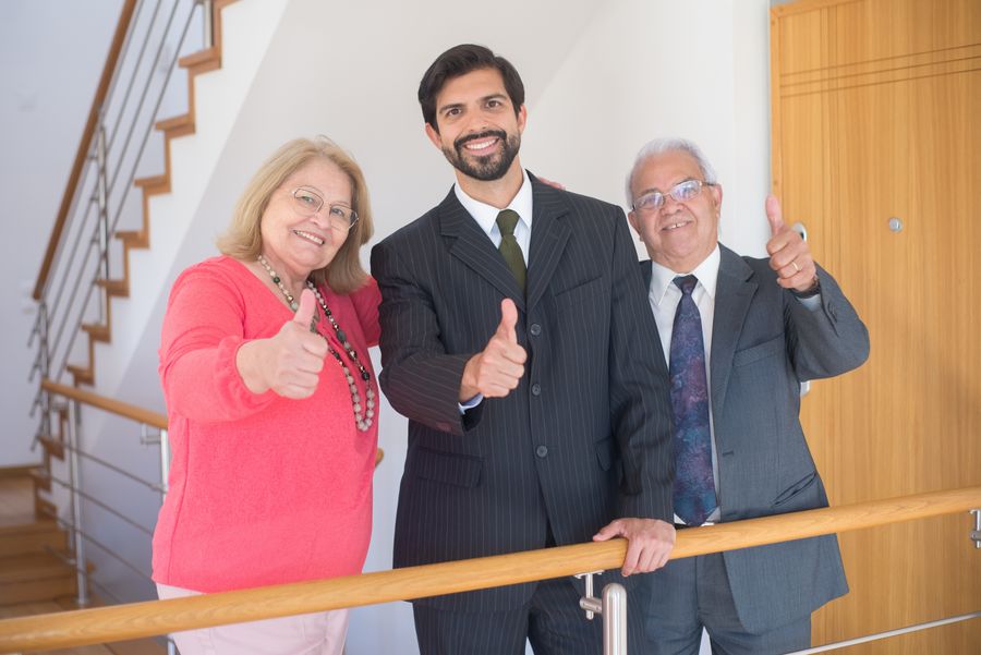 Three satisfied clients giving a thumbs up in a bright office