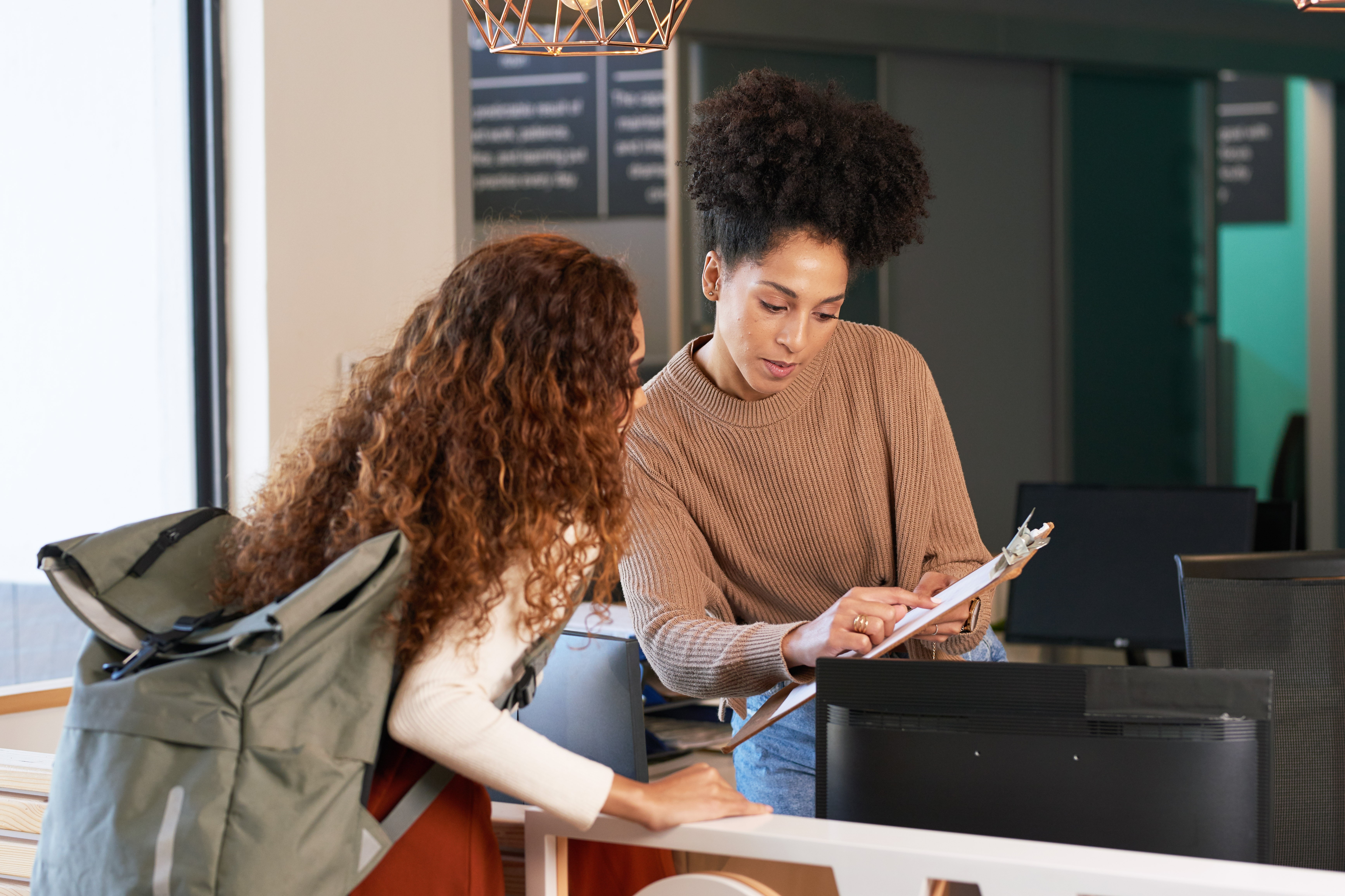 A teacher and a student looking at materials on a clipboard