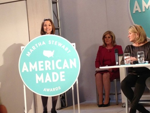 a woman giving a speech on the stand with the Martha Stewart American Made awards logo