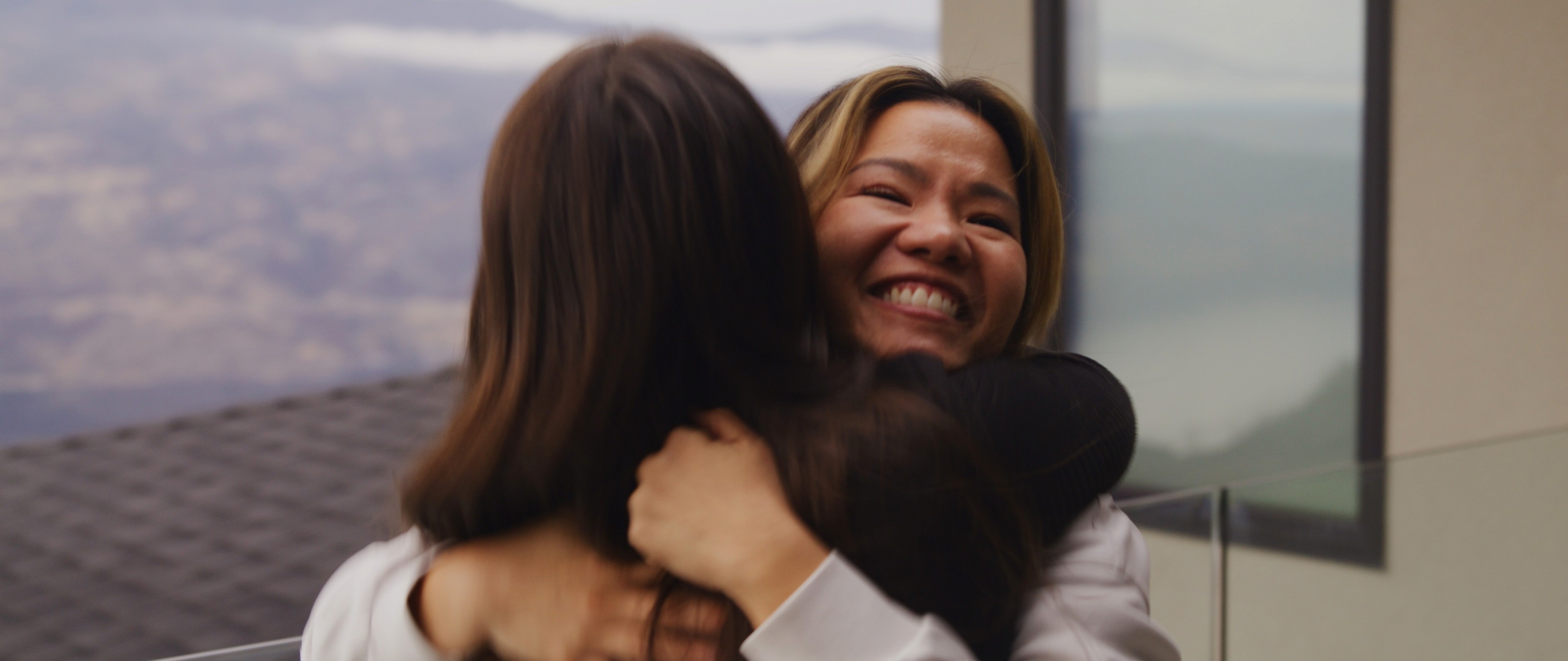 Two women hugging warmly, one smiling joyfully