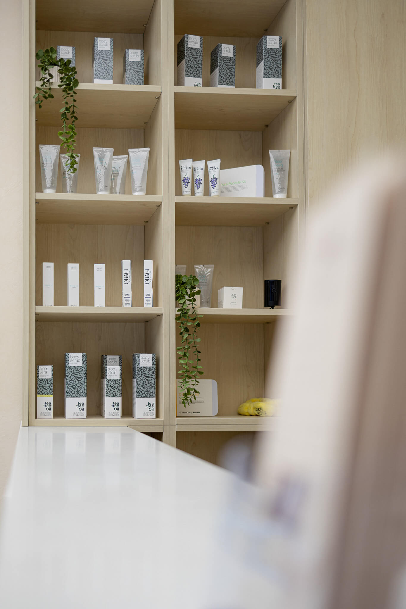 Close-up of skincare and beauty products displayed on wooden shelving in clinic interior.