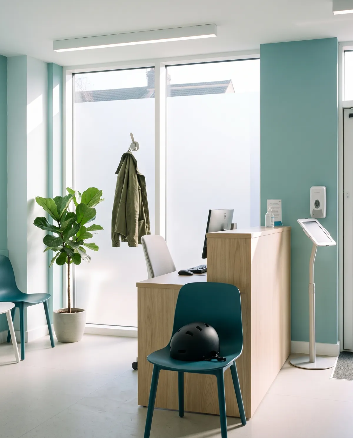 A coat and a bike helmet left on the teal chair in reception