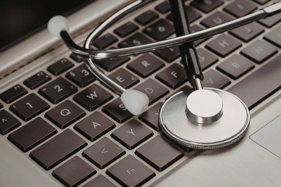 ai pharmacy software represented by a medical stethoscope resting on top of a laptop keyboard in a close-up shot.