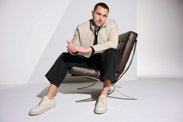 A model in a chair wearing an off white cream quilted liner jacket.