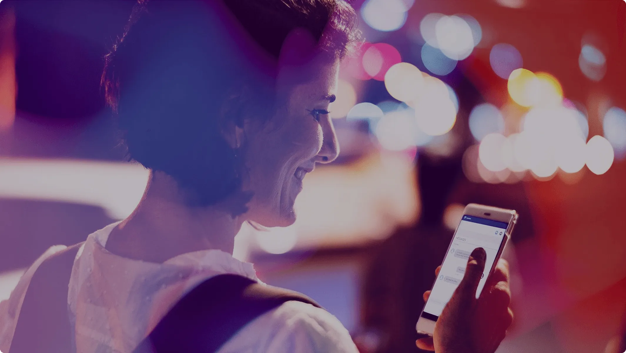 A woman looks at her phone, smiling