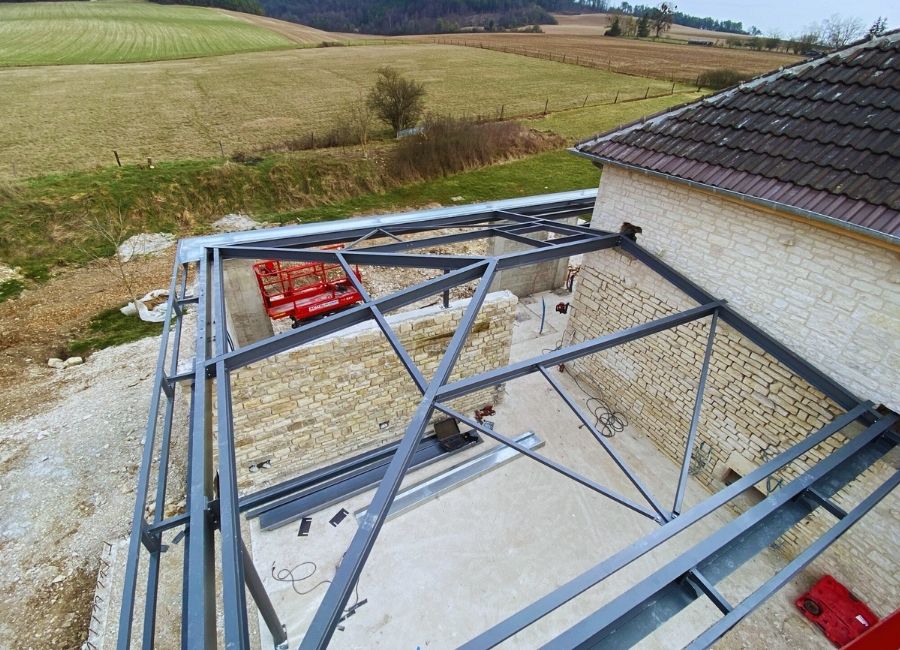 Matériaux et nacelle élévatrice sur chantier de rénovation, avant pose de la charpente métallique.
