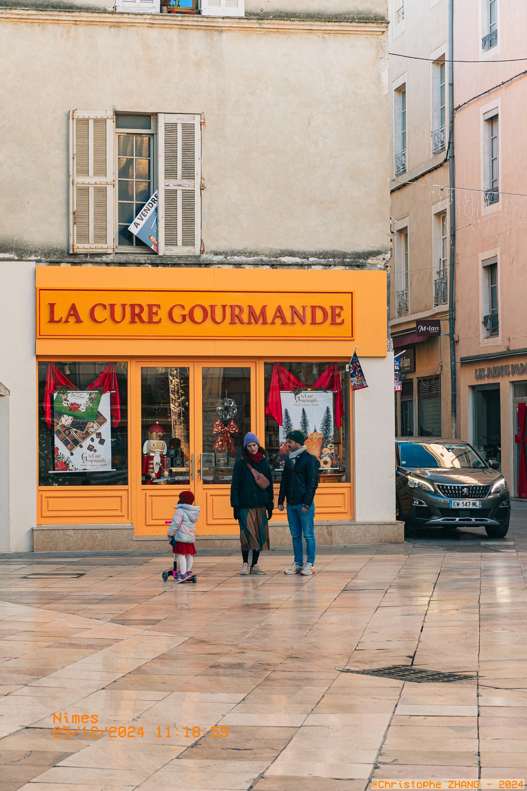 Famille devant la boutique La Cure Gourmande à Nîmes.