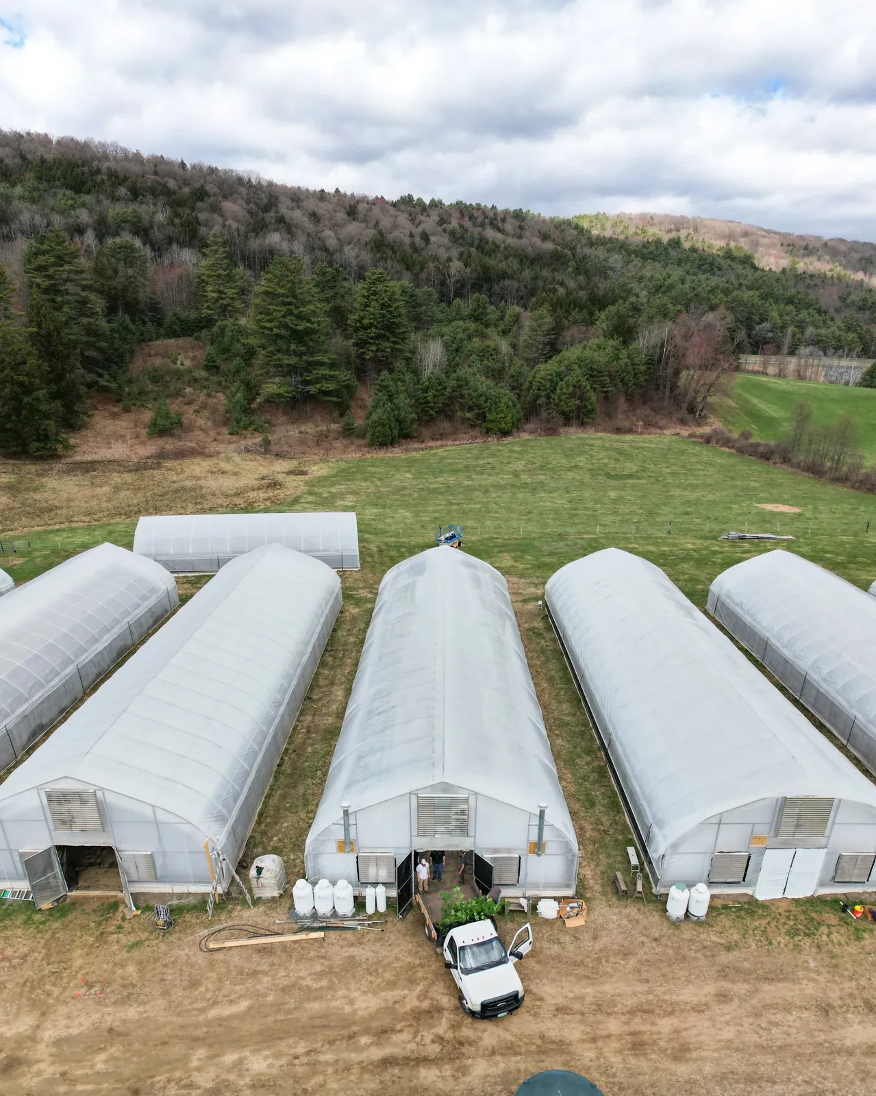 Aerial view of Sunkissed Farm's greenhouse structures nestled against the Green Mountains in Windsor, Vermont
