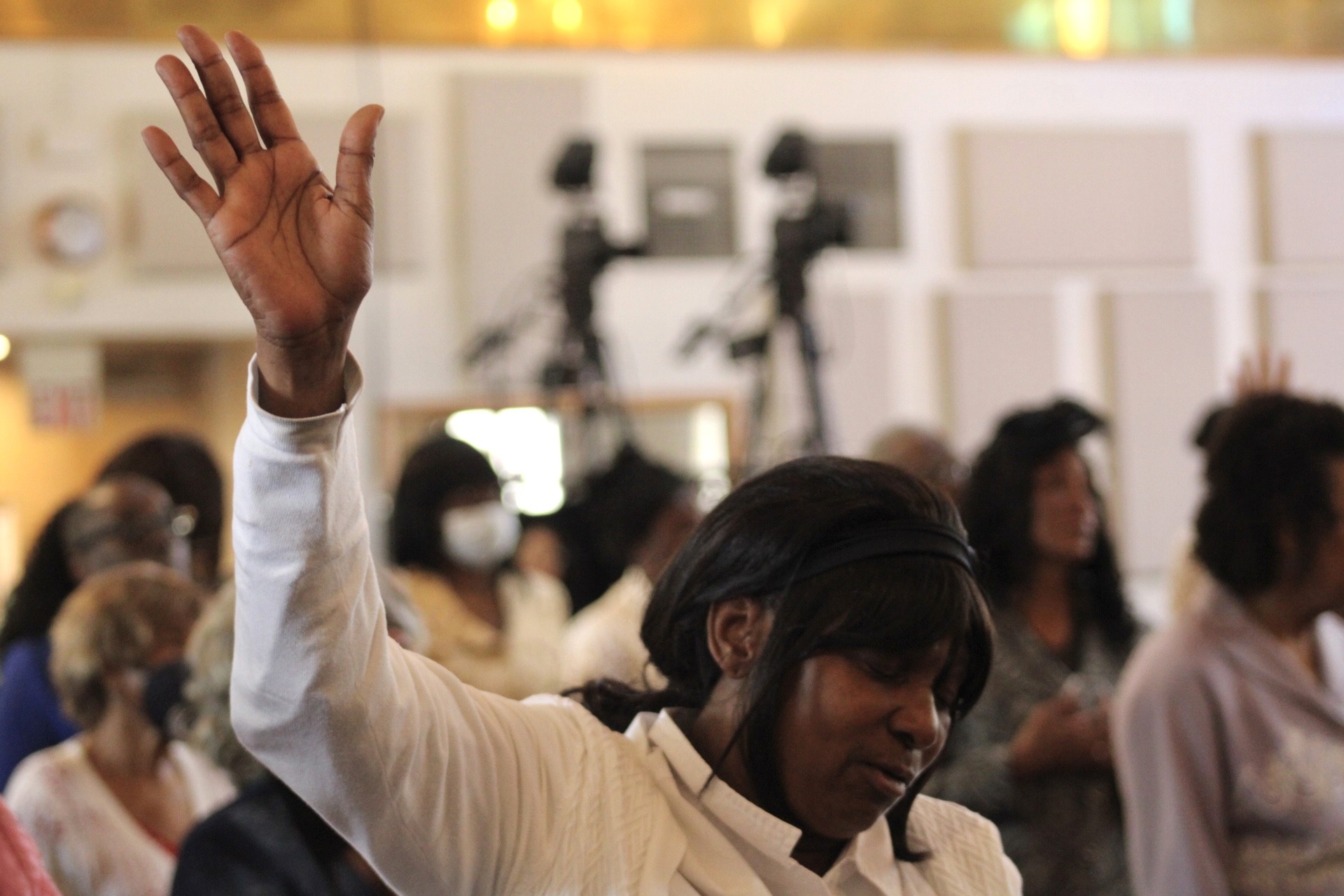Congregation raising hands in worship during a service at Peace Apostolic Church