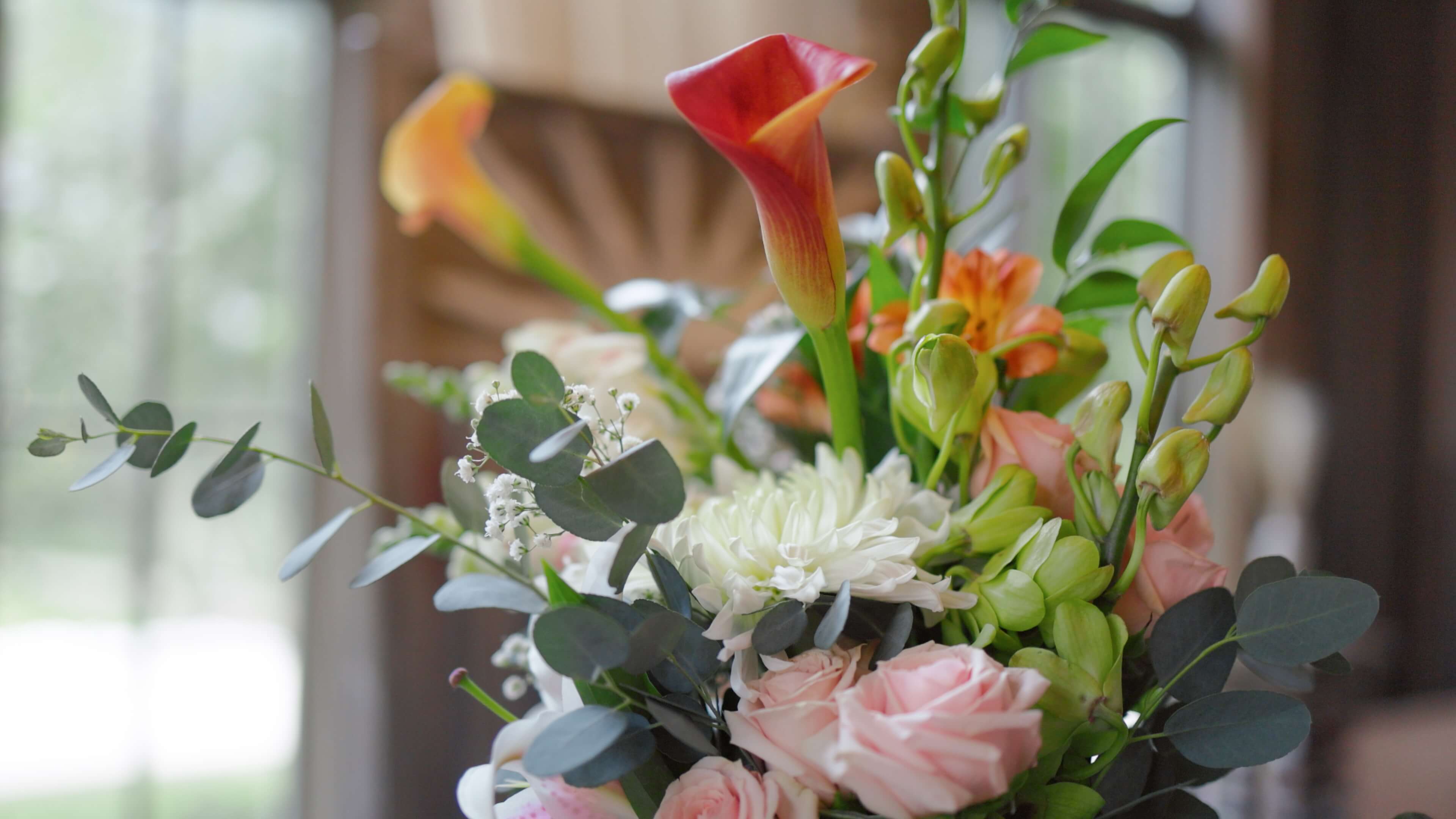 A brightly colored bouquet of flowers in front of a window