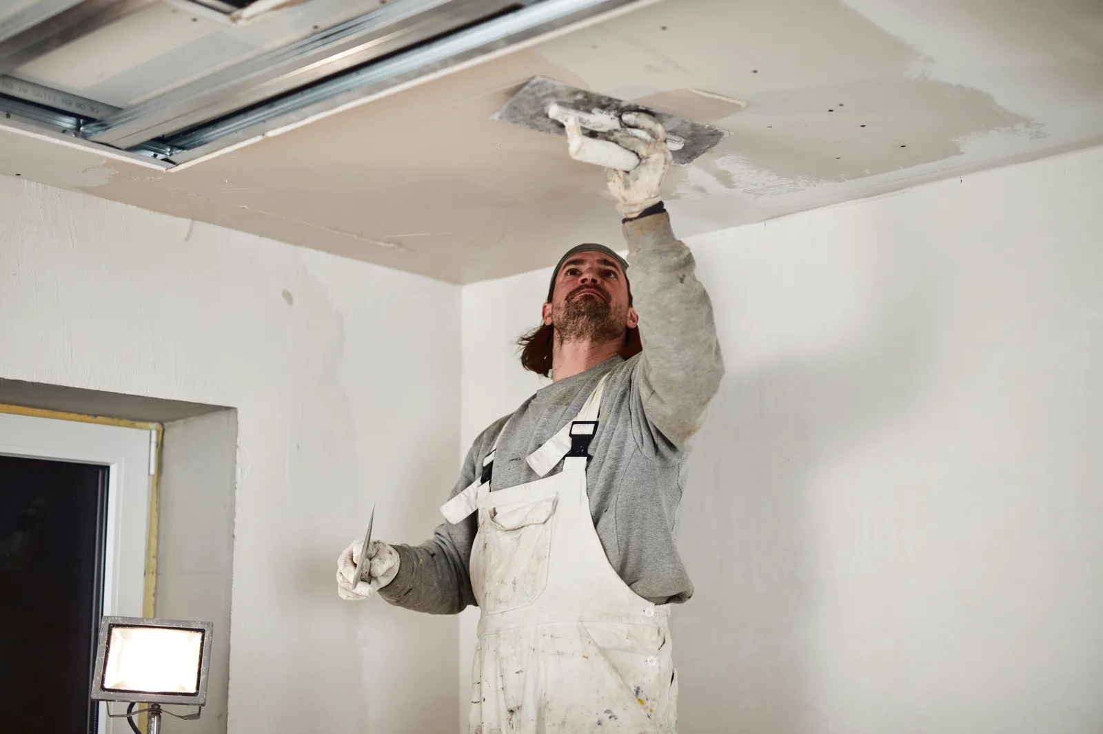 Worker applying plaster to ceiling with trowel