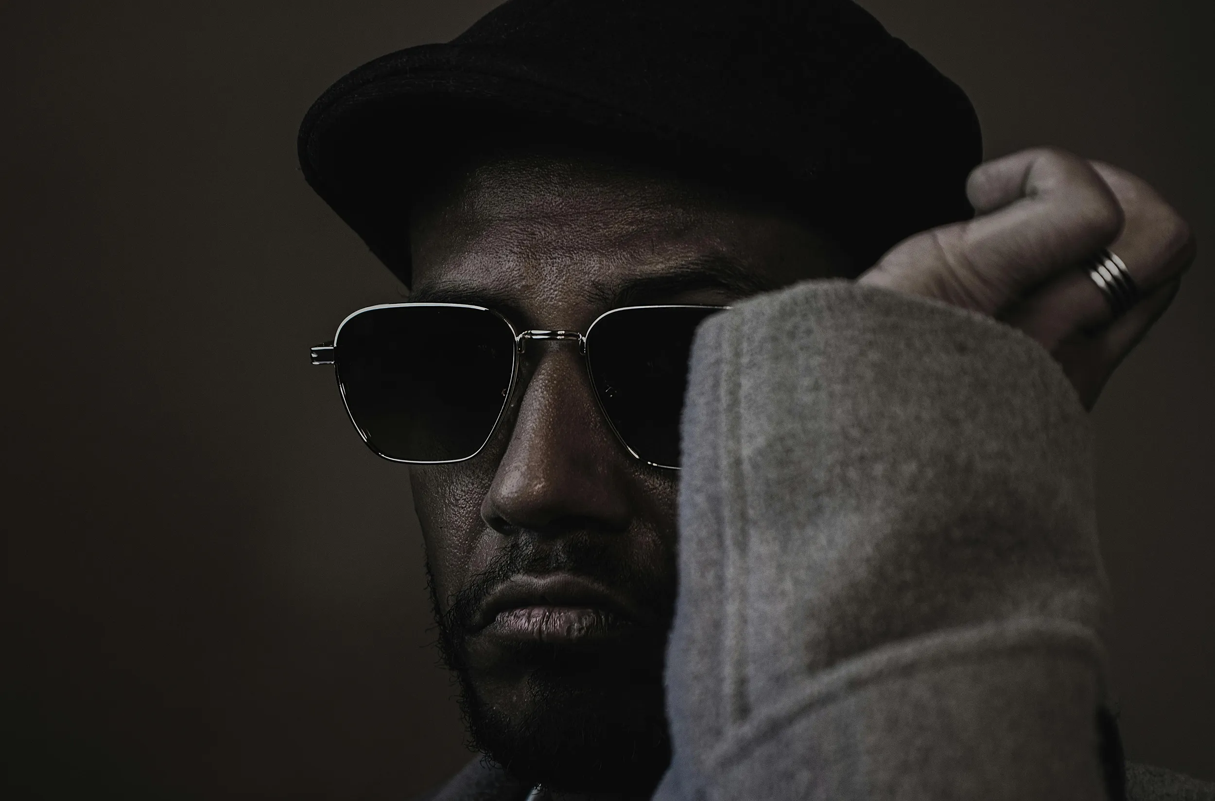 Moody portrait of man wearing sunglasses and hat, minimalist fashion photography