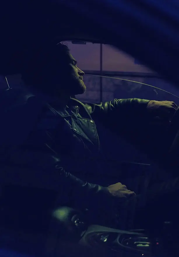 Man driving at night with hand on steering wheel