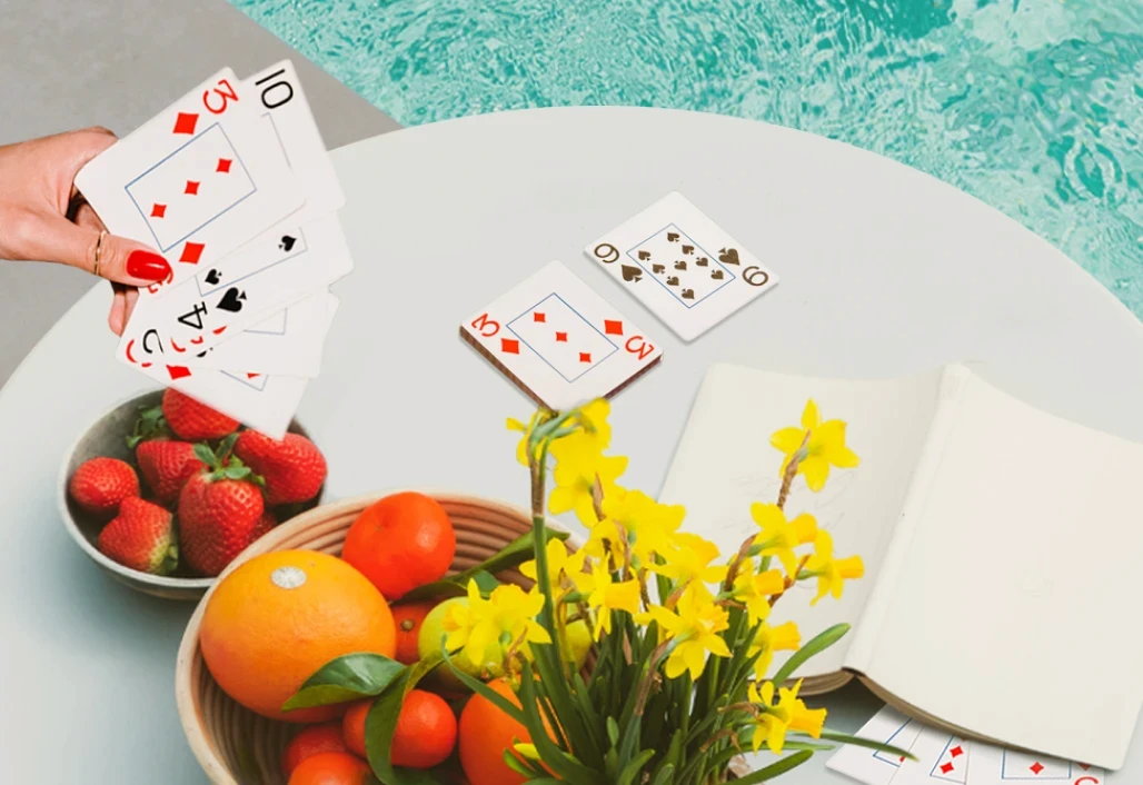 A woman laying cards, while relaxing by the poolside, enjoying a sunny day together.