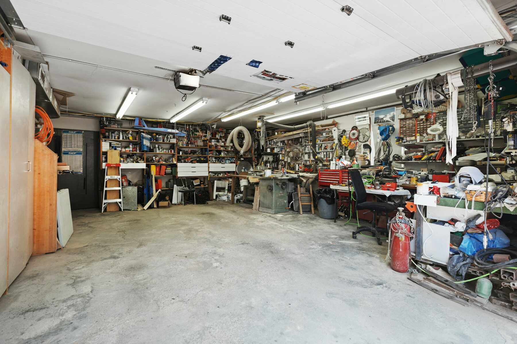 Cluttered garage packed with tools, shelves, and equipment