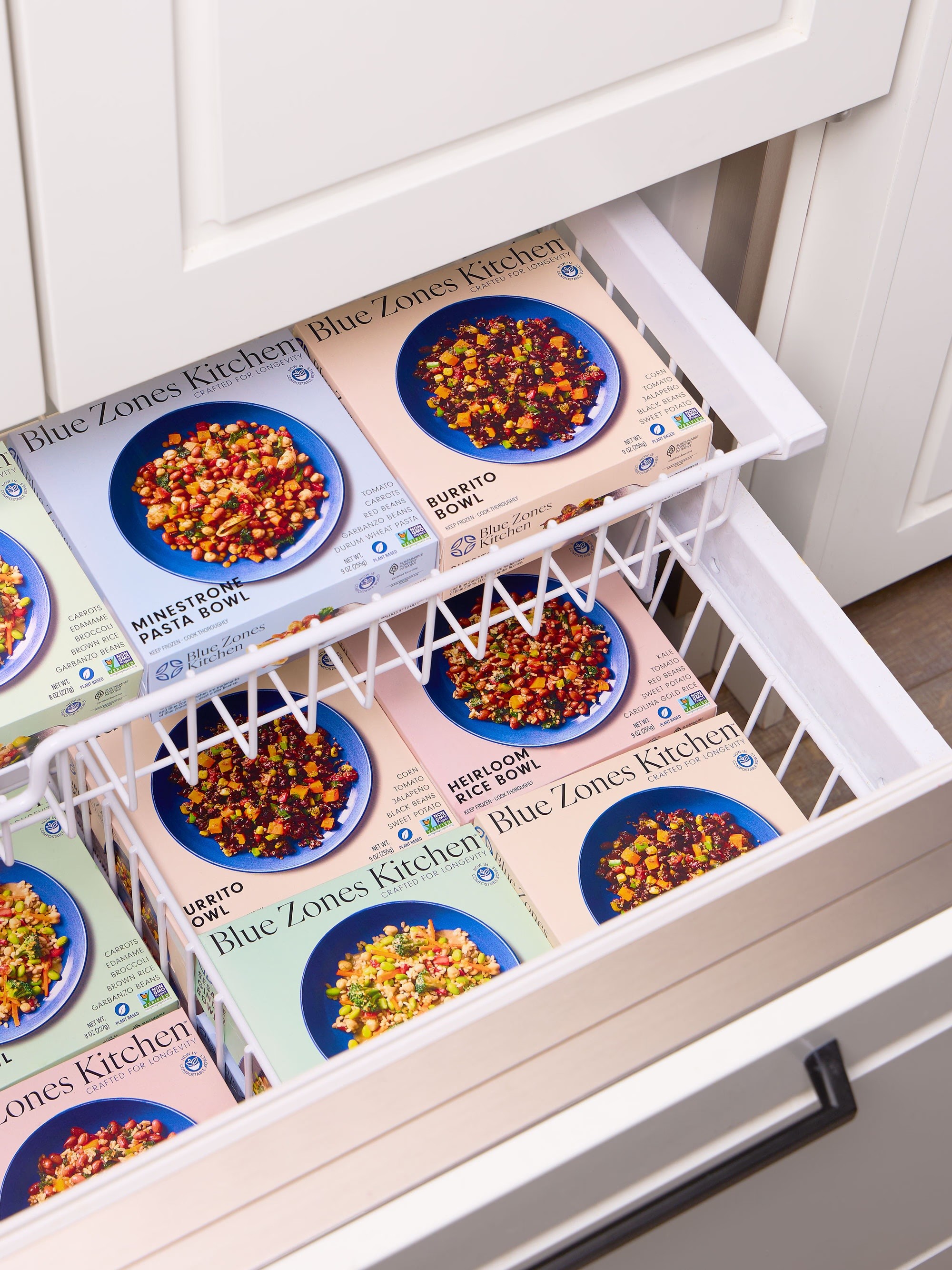 Drawer of frozen Blue Zones Kitchen meals neatly organized in a white freezer basket.