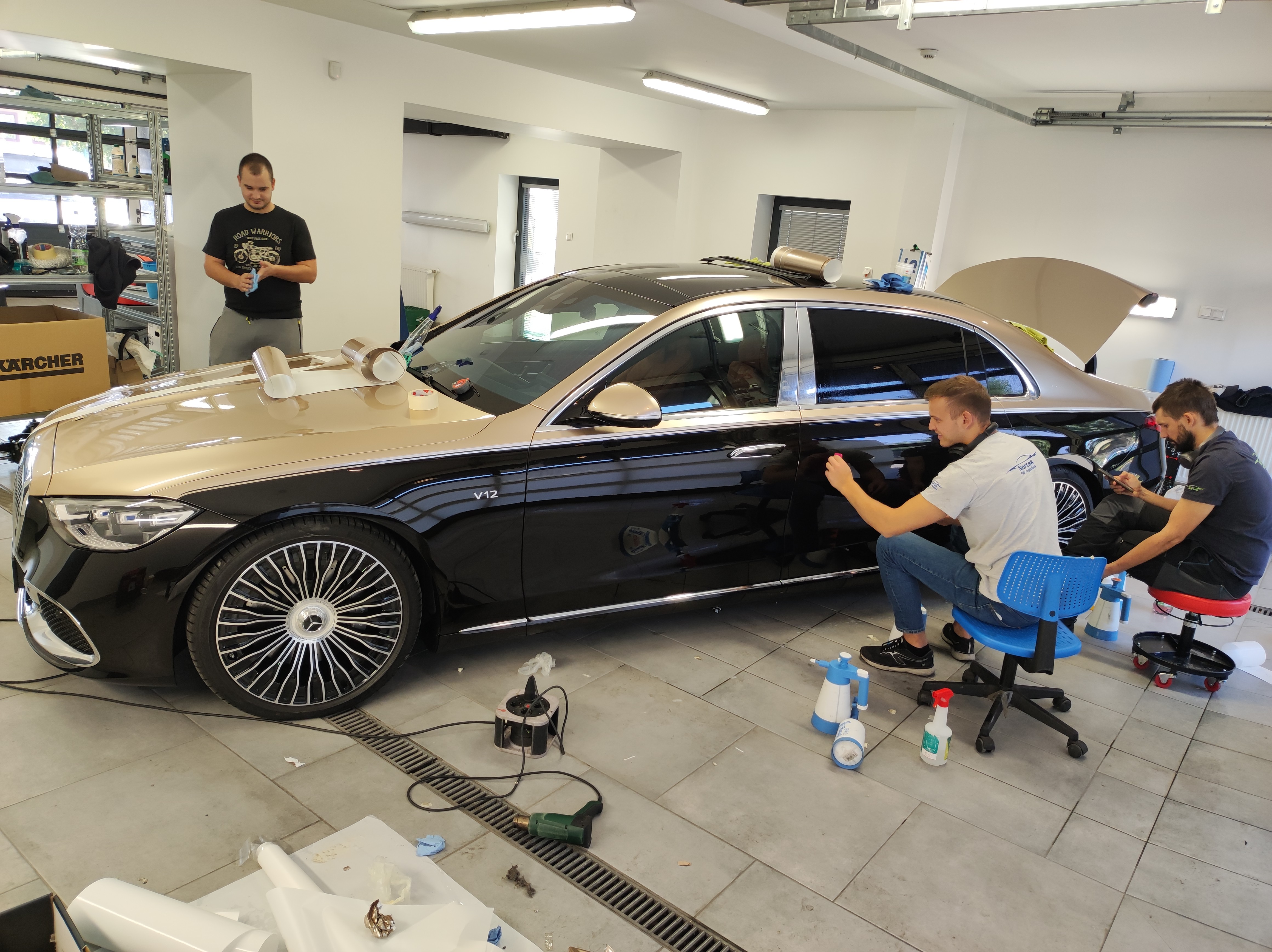 Három szakember dolgozik egy Mercedes-Maybach luxusautó prémium kéttónusú, arany-fekete autófóliázásán (wrap) a Nortek műhelyében.