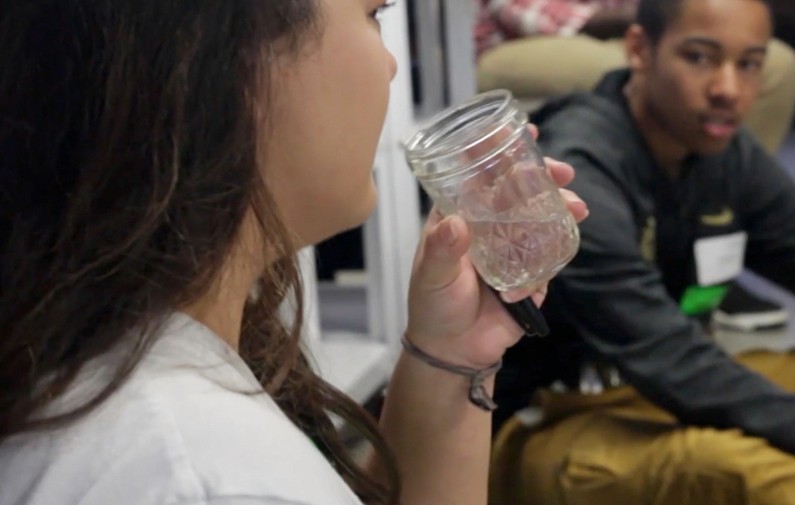 Teen drinking glass of water while another teen watches