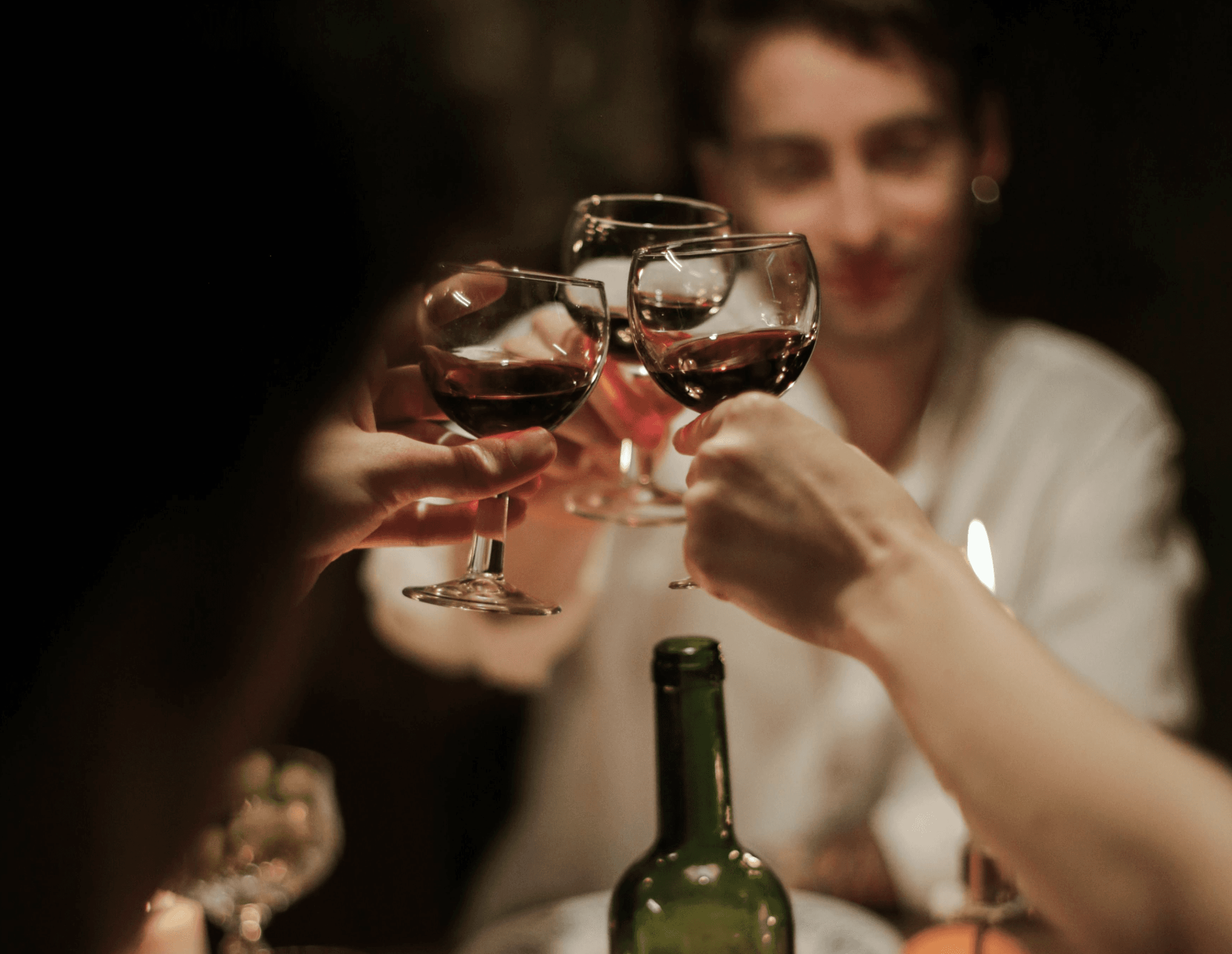 Three people raising their glasses together for a cheers.