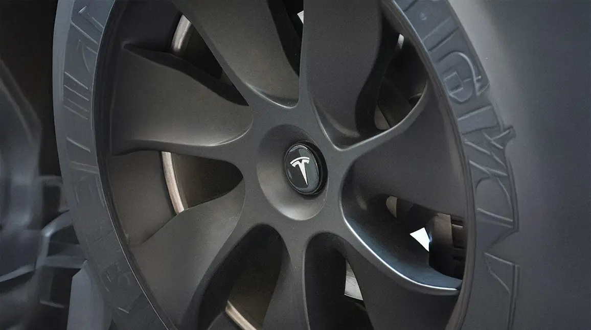 Close-up of a Tesla wheel representing electric vehicle body repair services.