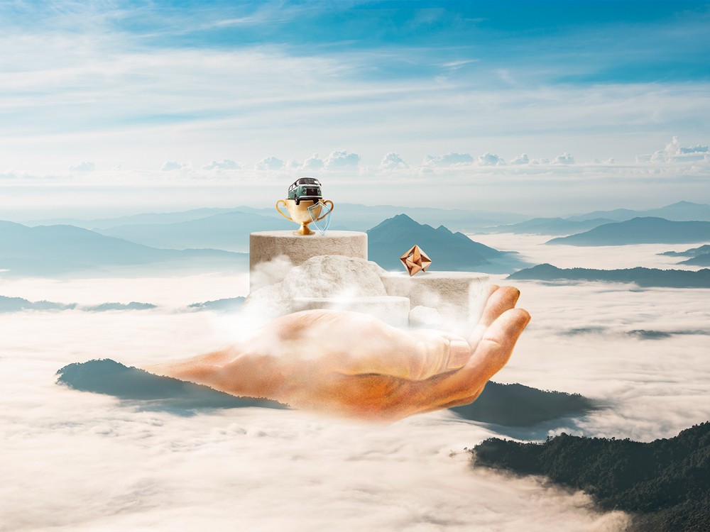 Mano sosteniendo trofeo en paisaje montañoso con cielo despejado y nubes bajas.