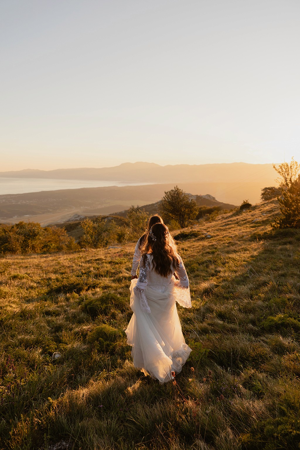 Married couple walking down the hill, overlooking the sea, into the sunset