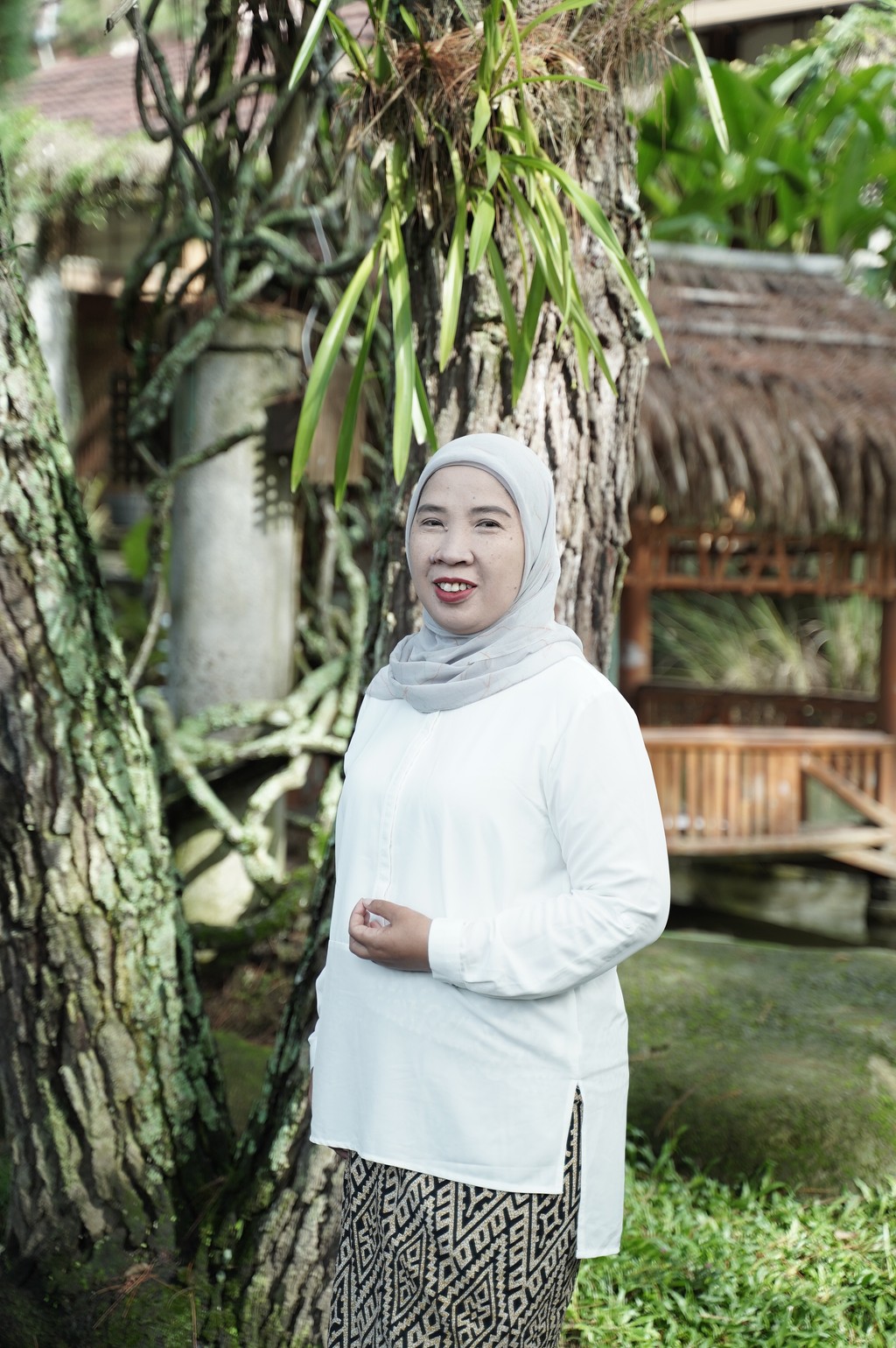 A winding road cuts through rocky terrain, surrounded by patches of green grass and illuminated by sunlight.