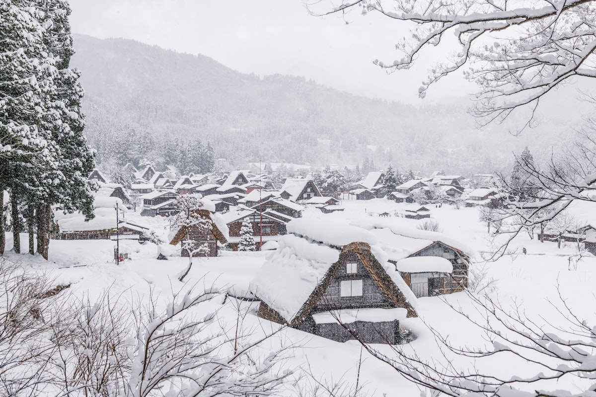 A snow-covered traditional thatched-roof village in the Japanese Alps at dusk in winter
